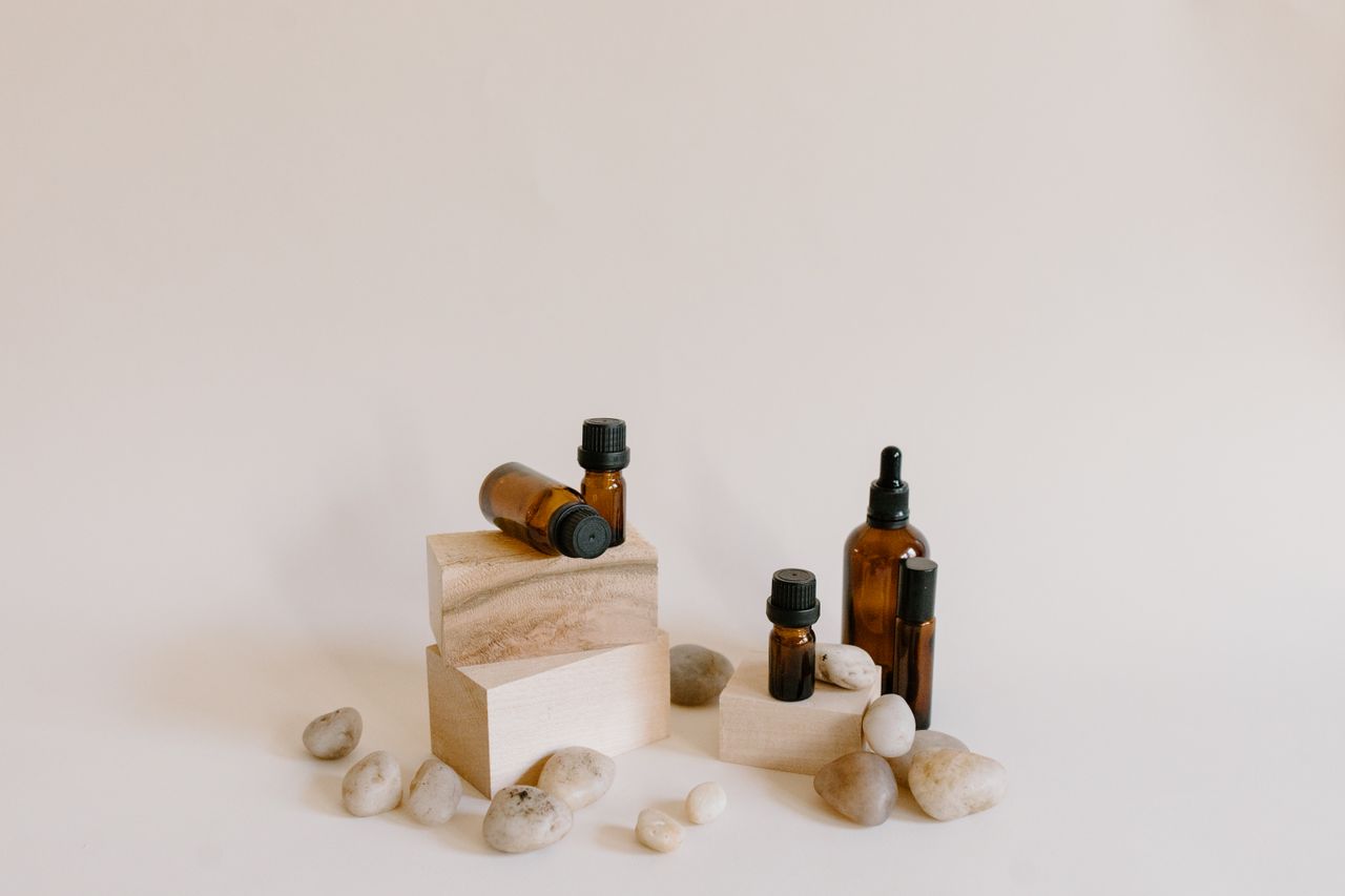 Still life composition of essential oil bottles with stones on a neutral background.